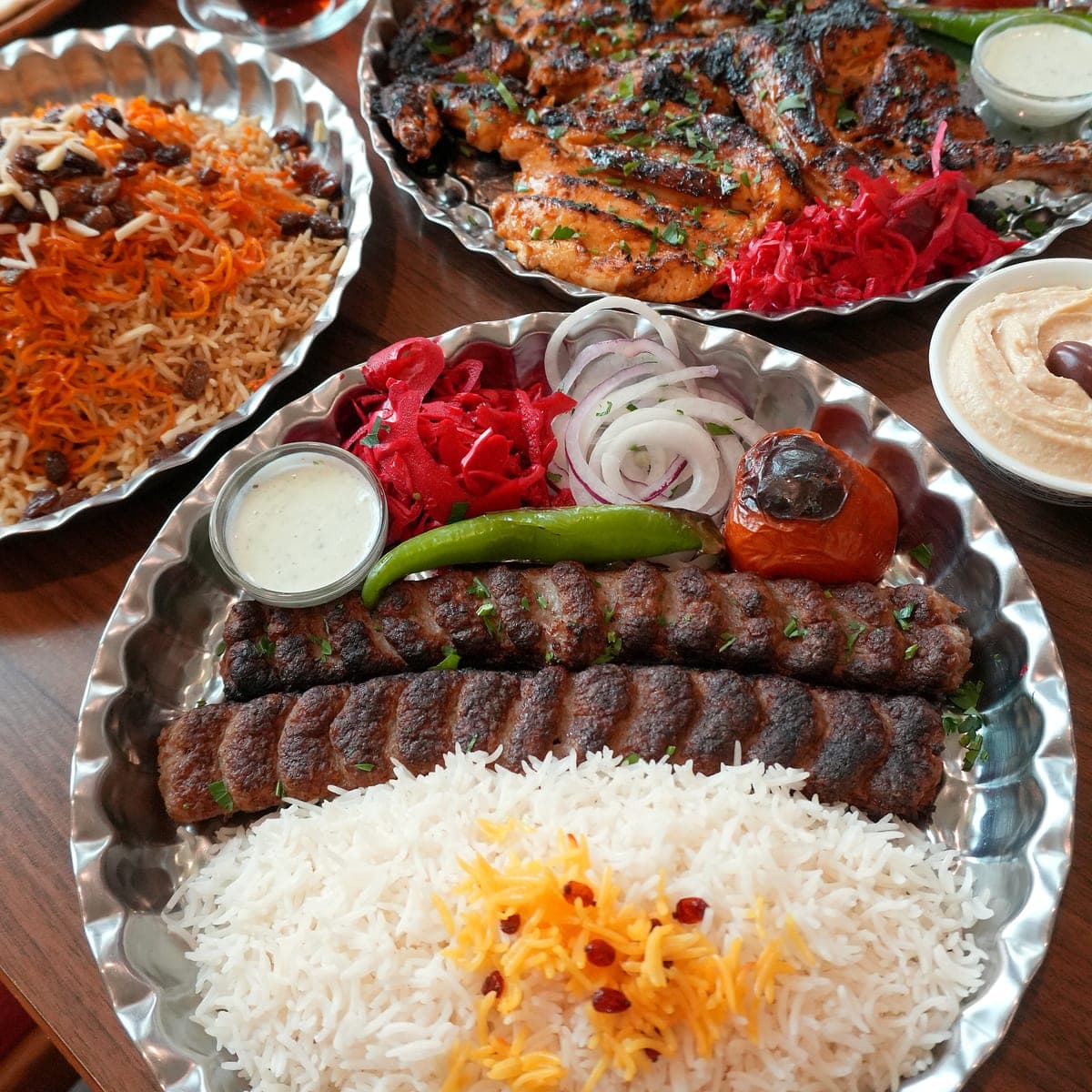 Tafel mit Kubideh, Safranreis, gegrilltem Huhn und Kabuli Palau im Fereshteh Restaurant Floridsdorf